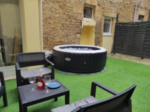 un patio con vasca idromassaggio, tavolo e sedie. di 2-Le Tropical - Jaccuzi - Sarlat - Centre ville a Sarlat-la-Canéda