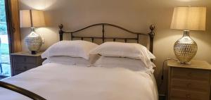 ein Schlafzimmer mit einem Bett mit weißer Bettwäsche und zwei Lampen in der Unterkunft Dunsa Cottage Bakewell Peak District in Bakewell + 5 Fotos