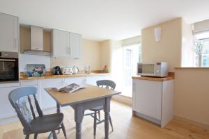 eine Küche mit einem Tisch, Stühlen und einer Mikrowelle in der Unterkunft Dunsa Cottage Bakewell Peak District in Bakewell