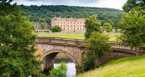 a bridge over a river in front of a large building at Rowsley Cottage Bakewell Peak District in Bakewell