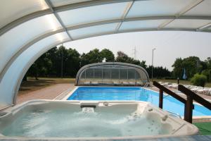 a hot tub under an archway with a swimming pool at Hotel Ovit in Keszthely
