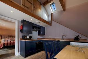 une cuisine avec des armoires bleu foncé et un escalier dans l'établissement Dipper Cottage Upperdale Peak District, à Buxton