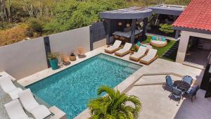 - une vue sur la piscine avec des chaises et une maison dans l'établissement Bocobay Zen Garden Villa, à Noord
