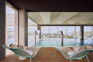 a room with a pool with chairs and a large window at Barceló Playa Blanca in Playa Blanca