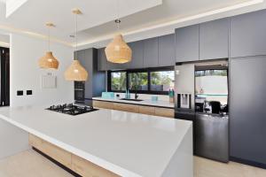 une cuisine avec des plans de travail blancs et des armoires bleues dans l'établissement Bocobay Zen Garden Villa, à Noord