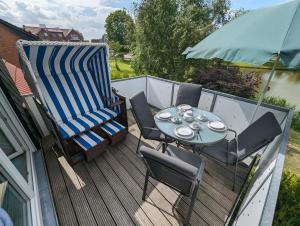 a patio with a table and chairs and an umbrella at FeWo Oldeoog OG - Horumersiel in Horumersiel
