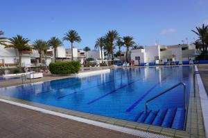 a large swimming pool in a resort with palm trees at Primavera Tranquil Retreat 2-Bedroom Apartment with Balcony, Garden View & Fiber WiFi in Arona