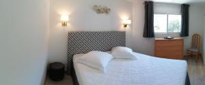 una camera con un letto bianco con due cuscini di Duplex à 100 m de la plage a Grosseto-Prugna