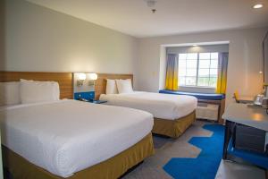 a hotel room with two beds and a desk at Microtel Inn & Suites by Wyndham Daphne in Daphne +45 photos