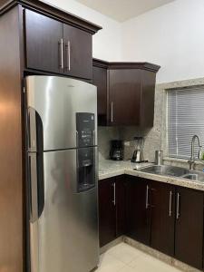 Una cocina con refrigerador de acero inoxidable y gabinetes de madera. en Casa Grande con Jacuzzi cerca de ctra MochisTopo, en Los Mochis