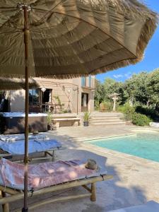 a patio with two tables and an umbrella next to a pool at Nouveauté Exceptionnelle Très belle villa au pied du Mont Ventoux in Bédoin