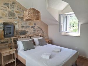 a bedroom with a large white bed with a stone wall at Stone house Gazda in Omiš