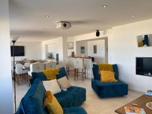 ein Wohnzimmer mit blauen Sofas und ein Esszimmer in der Unterkunft La Plage in Donville-les-Bains