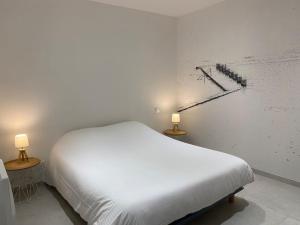 ein weißes Bett in einem Zimmer mit zwei Lampen in der Unterkunft La Plage in Donville-les-Bains