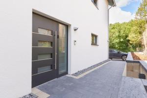 a black door on a white house with a driveway at HomeME 1 I zentral I NETFLIX I Küche I Parkplatz I kliniknah in Bad Oeynhausen