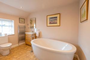 a bathroom with a tub and a toilet and a sink at Ball Cross Farmhouse Bakewell Peak District in Bakewell +61 photos