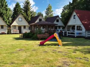 a playground with a slide in a yard with houses at Domki Letniskowe Bryza in Jarosławiec +2 photos