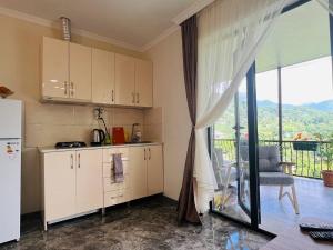 a kitchen with white cabinets and a view of a balcony at 8 mountains Cottage near Chakvi in Gorgadzeebi