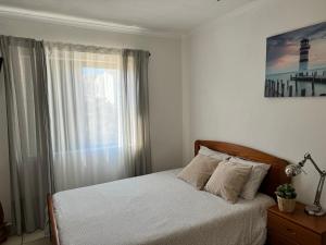 a bedroom with a bed with white sheets and a window at Apartamento JB - Dona Ana in Lagos