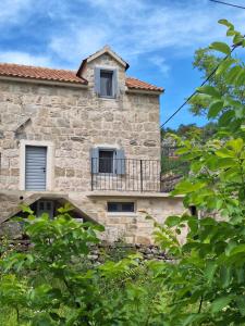 an old stone house with a balcony and trees at Stone house Gazda in Omiš