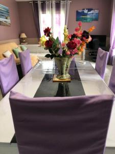 un vase de fleurs sur une table avec des chaises violettes dans l'établissement Maison Solyne Andernos les Bains, à Andernos-les-Bains