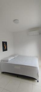 uma cama num quarto com uma parede branca em Cobertura Duplex com 3 Quartos na Praia dos Milionários Ilhéus - Ba - Mar Bello em Ilhéus mais 14 fotografias