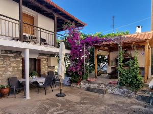 a patio with a table and chairs and purple flowers at Nikolaos House in Ayios Nikolaos Sithonia