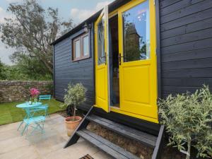 Una pequeña casa con una puerta amarilla y una mesa. en Tower Hut, en Ryde