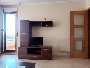 a living room with a tv on a wooden entertainment center at Edificio Fonte de Ons con piscina in Noalla