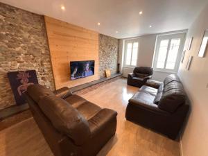 ein Wohnzimmer mit Ledermöbeln und einer Steinmauer in der Unterkunft Appartement centre-ville très spacieux avec 4 chambres in La Tour-du-Pin