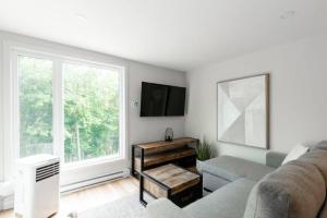 a living room with a couch and a window at Modern Lodge Pool & Spa Mont-Tremblant in Mont-Tremblant