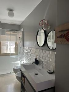 a bathroom with a sink and a toilet and mirrors at Vecchio Calzaturificio Verducci Affittacamere in Montegranaro +63 photos