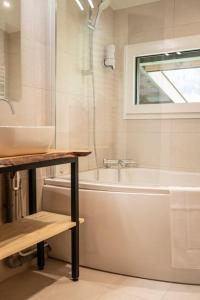 a bathroom with a tub and a sink and a bath tub at Venez chez vous - Chalet le Dahu in Rovagny