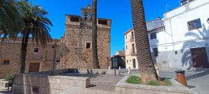 un edificio con una torre dell'orologio e una palma di Pizarro 23, en el corazón de Cáceres a Cáceres