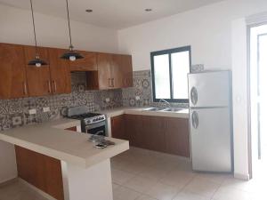 eine Küche mit Holzschränken und einem weißen Kühlschrank in der Unterkunft Casa Cecilia in Cozumel