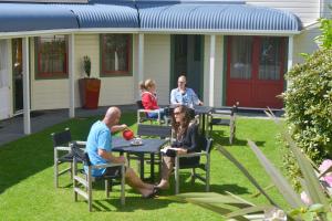 a group of people sitting at a table in a yard at Ducks & Drakes Boutique Motel & Backpackers in New Plymouth +15 photos