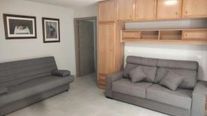 a living room with a couch and a chair at Apartamentos La Fuente Ribadeo in Ribadeo
