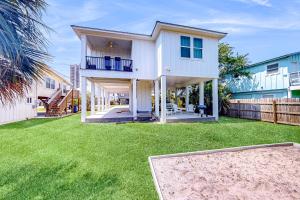 a large white house with a yard with a trampoline at Cactus Cove Hangout in Gulf Shores