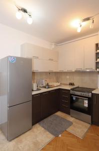 Una cocina con gabinetes blancos y un refrigerador de acero inoxidable. en Golden Royal M, en Kragujevac