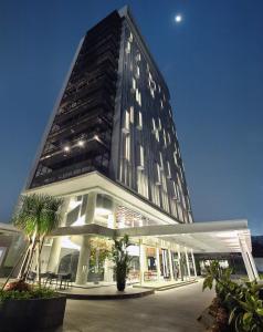 a tall black building with palm trees in front of it at Ra Premiere Simatupang Jakarta in Jakarta