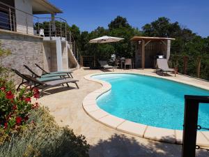 a swimming pool with chairs and a table at Villa Mare e Machja in Zonza