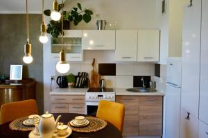 a kitchen with a table and a kitchen with white cabinets at Artystyczna przestrzeń z widokiem na jeziora in Iława