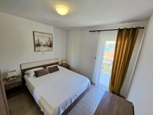 a bedroom with a white bed and a window at Apartments Villa Julija in Lumbarda