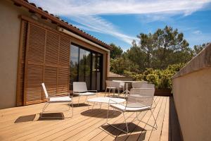 una terraza con sillas blancas y una mesa. en La maison de Brigitte, en LʼIsle-sur-la-Sorgue
