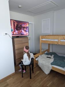 a little girl sitting in a chair in a bedroom with a bunk bed at Leilighet sentralt i Stryn in Stryn
