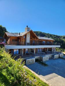 a house on a hill with water in front of it at Pousada Maple Monte Verde in Monte Verde