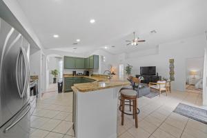 a kitchen and living room with green cabinets and a counter at Stunning 4-bedroom Villa w/ Pool - Close to Disney Parks and Gulf Courses! in Davenport