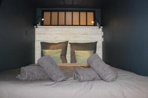 a bed with four pillows on top of it at Le Petit Moulin in Gradignan