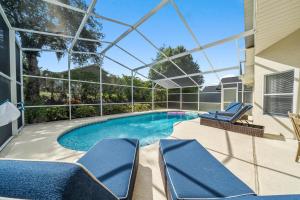 a swimming pool with two blue chairs and a building at Stunning 4-bedroom Villa w/ Pool - Close to Disney Parks and Gulf Courses! in Davenport