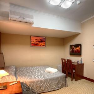 a hotel room with a bed and a desk and a table at Voyage Hotel in Almaty